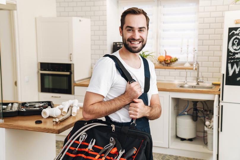 sms-marketing-agency for home service contractors  - image-of-plumber-man-smiling-and-holding-bag
